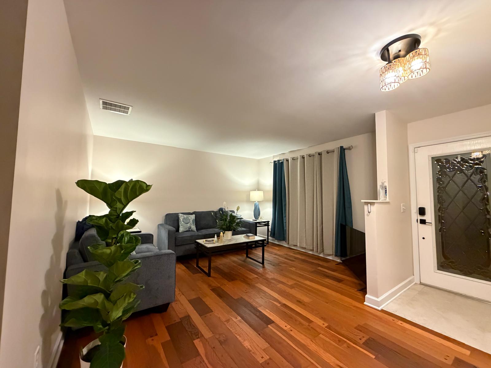 Spacious living room with blue sofas, wood floors, and plants