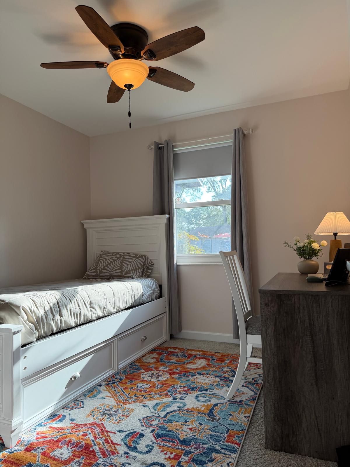 Kids’ room with a single bed, colorful rug, and desk