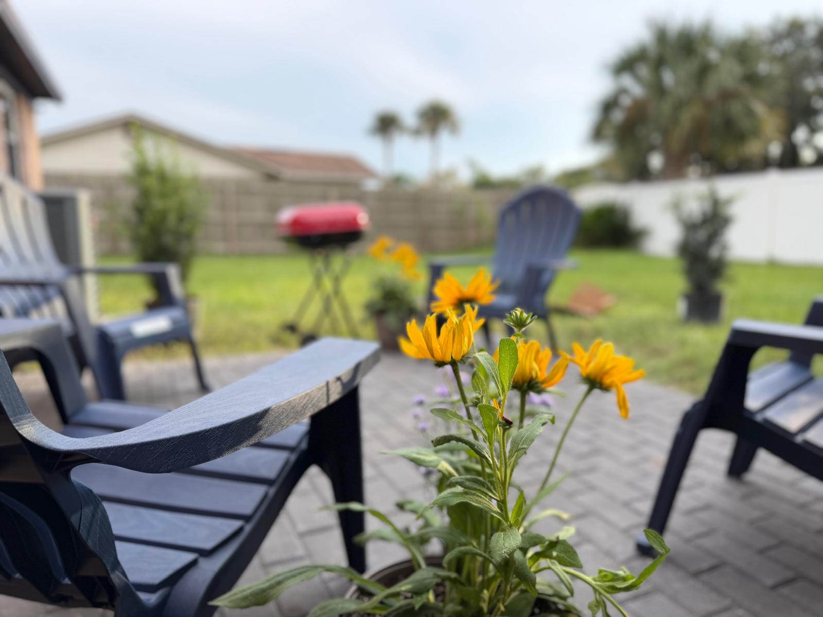 Patio seating surrounded by yellow flowers overlooking the lawn