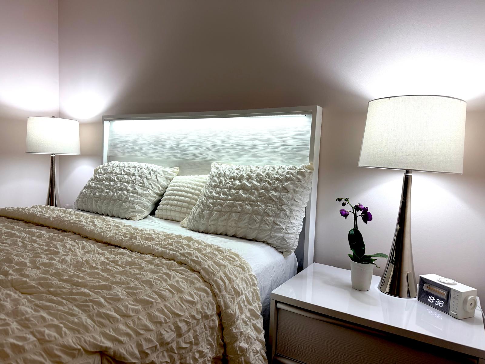 Queen bed with textured white bedding and bedside lamps